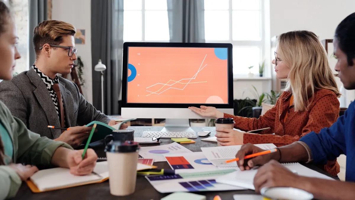 team meeting with a monitor showing a line chart